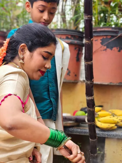 A moment of focus while cooking during the Pongal festival, surrounded by traditional elements like sugarcane and bananas.