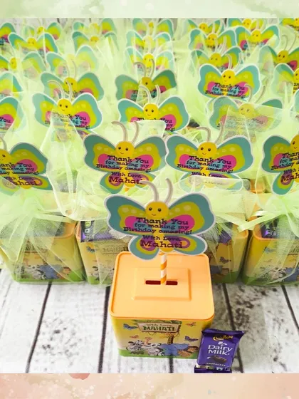 A full batch of the jungle-themed piggy banks, all wrapped and ready to be given out as party favors. The butterfly tags add a touch of whimsy.