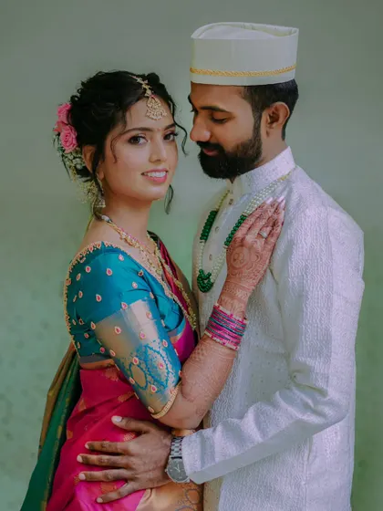 A lovely portrait of the couple, with the bride looking confidently at the camera. Her colorful saree and the groom's classic white attire make a striking pair.