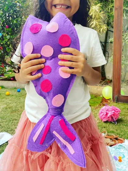 A proud smile with a handmade creation! This partygoer is showing off the colorful felt mermaid tail she made during one of our craft sessions, a perfect keepsake from a magical day.