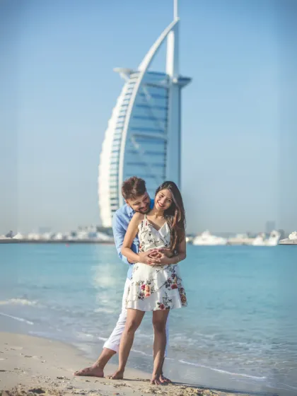 An iconic pre-wedding photograph with the couple posing playfully on a Dubai beach, with the magnificent Burj Al Arab in the background. This shot perfectly encapsulates the luxury and adventure of a destination shoot.