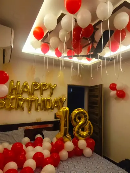 Celebrating a milestone 18th birthday with a classic red and white theme. The room is filled with balloons on the floor and ceiling, with large gold foil "18" numbers and a "Happy Birthday" banner as the centerpiece.