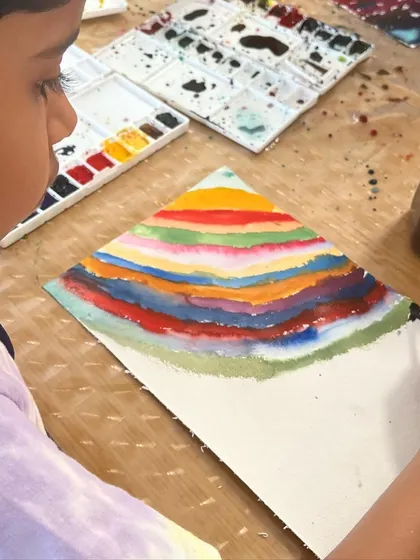 This artist is creating a colorful, layered pyramid. The focus here is on the process of layering colors and exploring how they interact, rather than on a perfect final product.