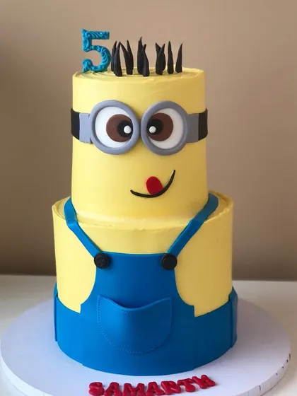A fun and mischievous two-tiered Minions cake. This bright yellow and blue design is perfect for a fan of the lovable characters.