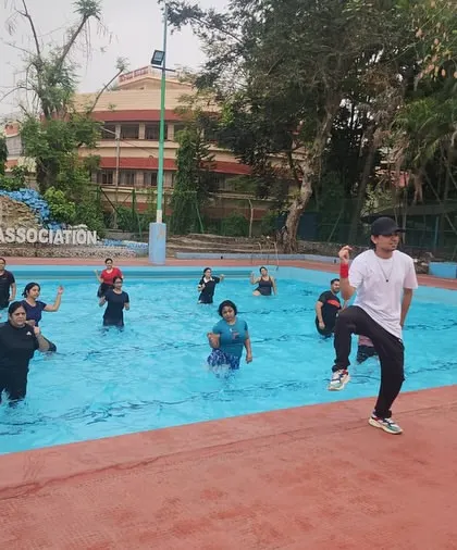 I lead the class from the side of the pool, demonstrating the next move for our aqua aerobics session.