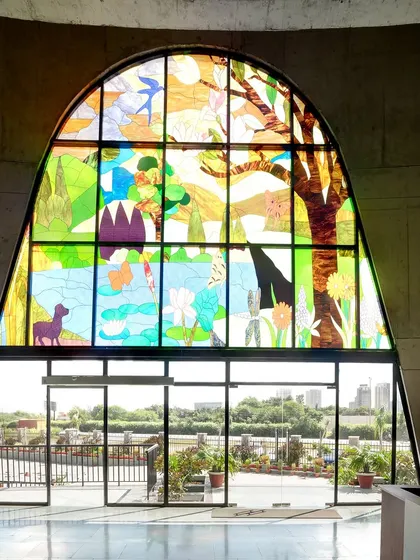 The view from inside the main entrance lobby, looking out through the 'Garden of Eden' stained glass window. The design allows natural light to filter through the coloured glass, creating an inspiring and contemplative atmosphere in the reception area.