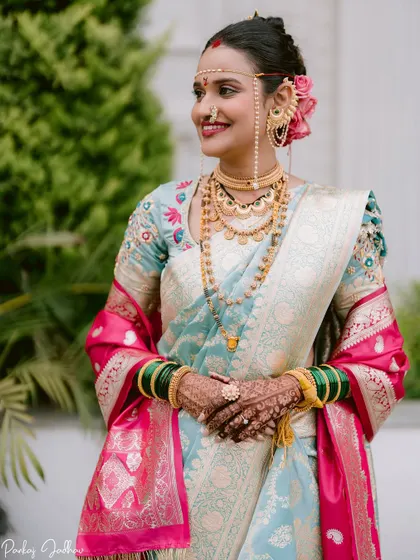 A stunning portrait of the bride, Kanchan, her traditional attire and jewelry shining against a natural green background.