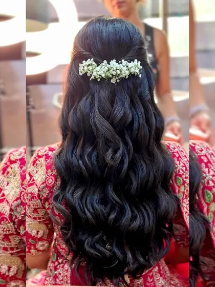 A simple and elegant half-up hairstyle with soft waves and a fresh baby's breath accessory.