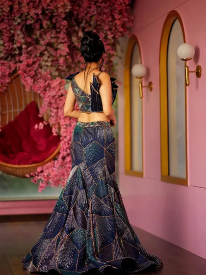 The back view of the sculpted geometric lehenga shows the intricate 3D shoulder details on the blouse. This is a design for a bride who wants to make a fashion-forward statement from every angle.