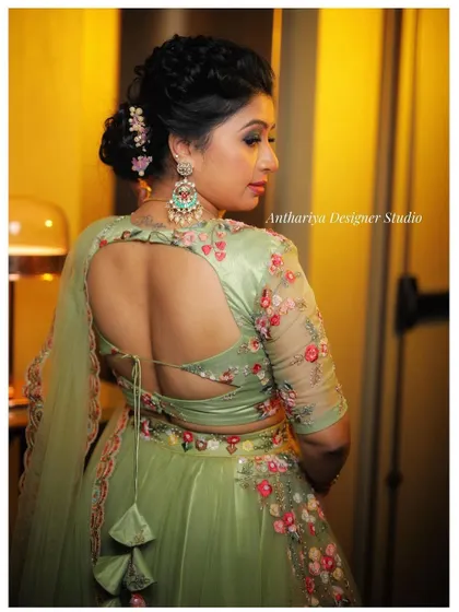 A view of the back of the pastel green lehenga, highlighting the stylish cutout and tassel details.
