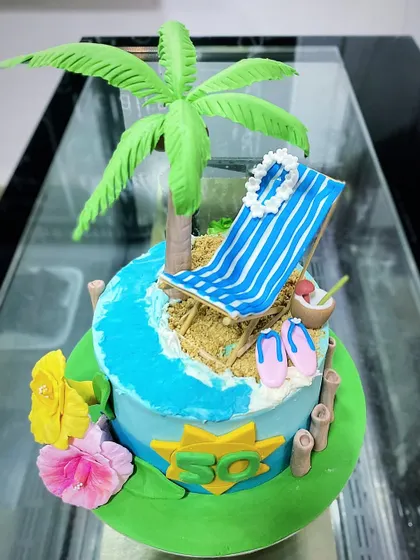 A fun, tropical beach-themed cake for a 50th birthday. This detailed cake features a fondant palm tree, a beach chair, and edible sand, bringing a vacation vibe to the celebration.