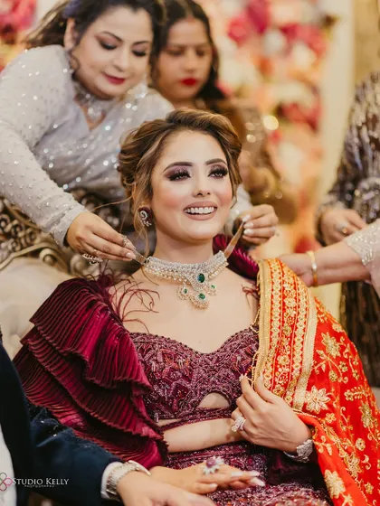 A heartwarming moment of the bride's family placing a necklace on her during the engagement ceremony.