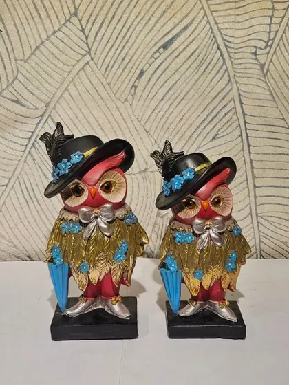 A very stylish and ornate owl couple, dressed in hats and holding umbrellas. This unique showpiece is for those who love detailed and whimsical decor.