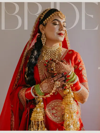 A stunning magazine-style portrait of the bride, capturing her serene expression and the intricate details of her red Sabyasachi lehenga and gold jewelry. A timeless image of bridal beauty.