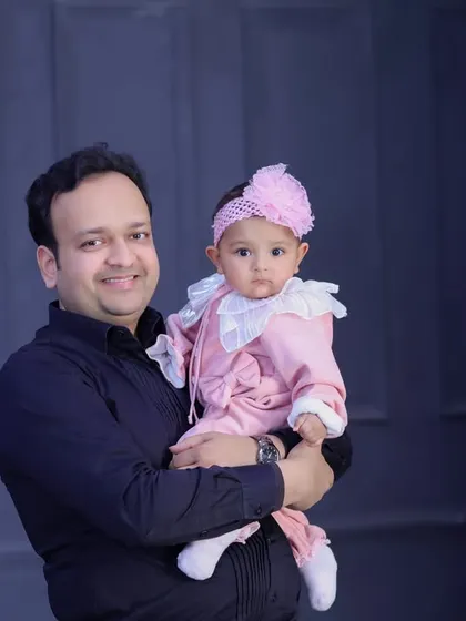 A classic father-daughter portrait. The simple, dark background and formal attire give this photo a timeless and elegant feel.