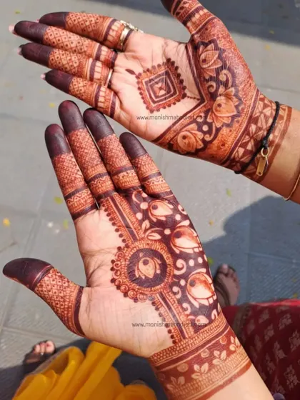 The beauty of a fresh henna stain. This design shows a mix of styles, with a geometric pattern on one hand and a floral mandala on the other, both featuring lotus motifs.