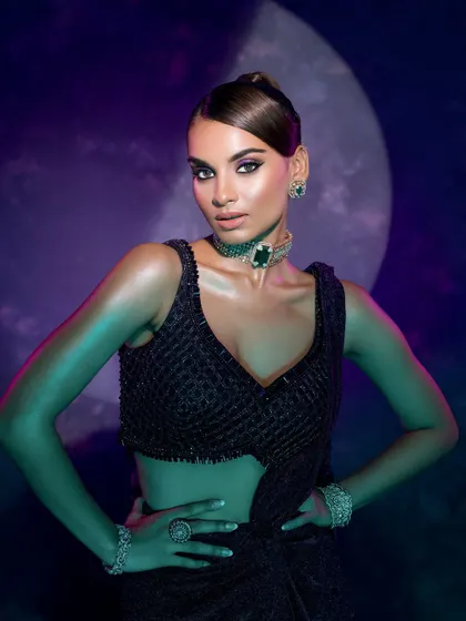 A powerful pose with dramatic lighting that sculpts the model's form and highlights the deep tones of the outfit and the sparkle of the jewelry.