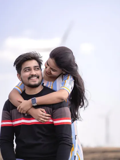 A playful moment with the windmills of Satara in the background. This hug from behind shows their comfortable and easy connection.