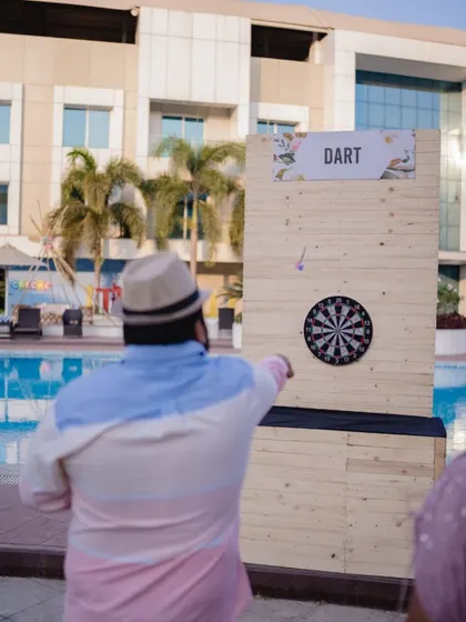 Guests enjoying a game of darts at the poolside carnival, one of the many interactive stations I can set up to entertain everyone.