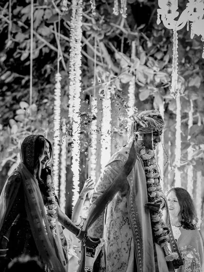 A candid black and white moment from the Pheras ceremony. This image captures the couple walking together, surrounded by the love and blessings of their family.