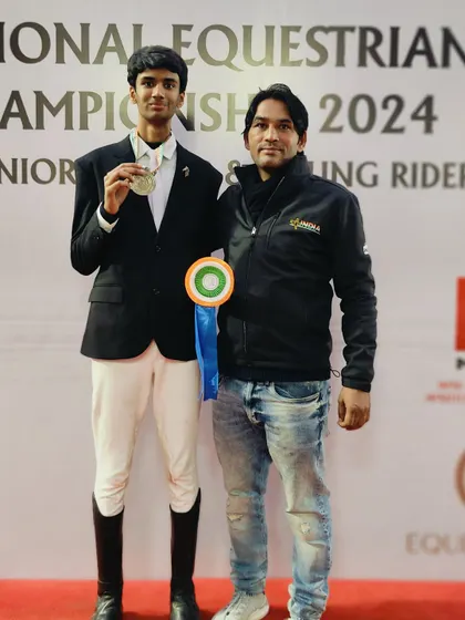 A coach proudly stands with his student, a silver medalist at the National Equestrian Championship. This one-on-one mentorship is key to our training approach.