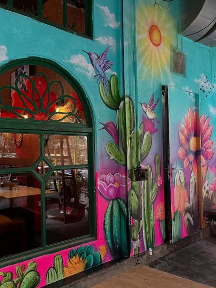 Another view of the colorful Mexican-themed mural, showcasing the lively composition of birds, cacti, and flowers.