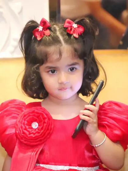 A cute portrait of a little girl in a red dress at her birthday party. We are patient and skilled at getting great photos of even the youngest children.