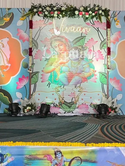 A closer view of the stage backdrop, which featured a serene illustration of Yashoda and Krishna, personalized with the baby's name, "Vivaan," in glowing letters.