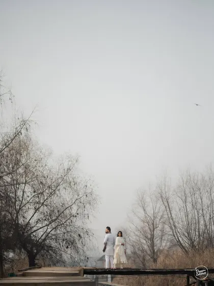 Looking up at the sky together, surrounded by the stark beauty of winter trees in Kashmir. This is a moment of shared peace and reflection, captured in a simple yet powerful pre-wedding photograph.