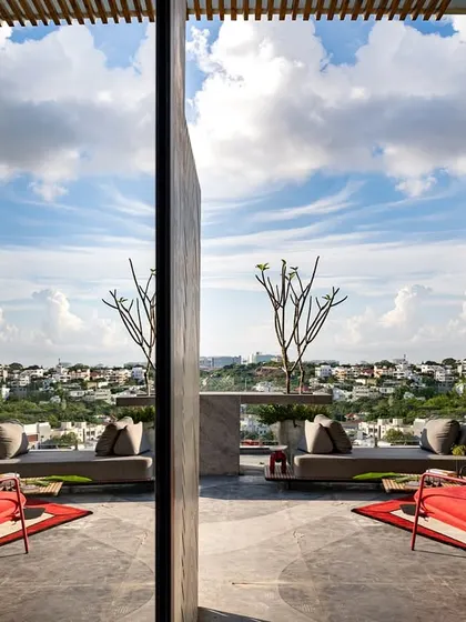 A reflected view of a rooftop terrace, showcasing the open sky, comfortable seating, and curated plants. The design creates a perfect urban vibe for relaxation and enjoying the city views.