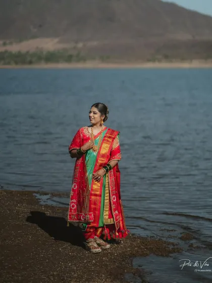 A beautiful bridal portrait by the water. The bride, in her traditional Maharashtrian saree, looks serene against the backdrop of the lake and hills.