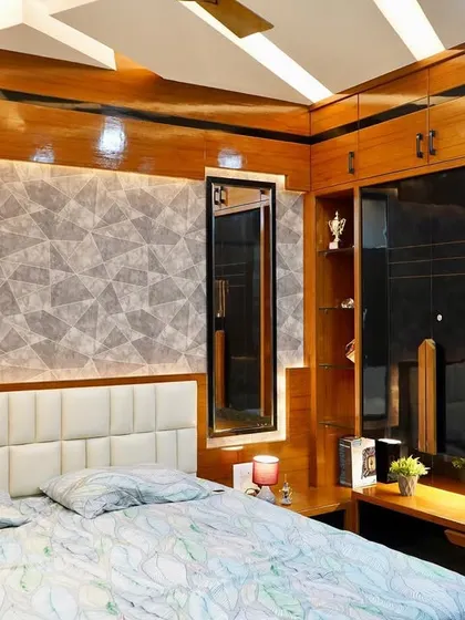 A bedroom design that combines glossy wood veneer with a textured grey wallpaper and a dark glass wardrobe. The false ceiling with its geometric design adds another layer of interest.