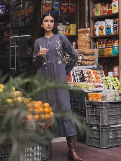 A campaign for a sustainable fashion brand, shot on location at a local market. The embroidered grey dress blends beautifully with the rustic, everyday environment.
