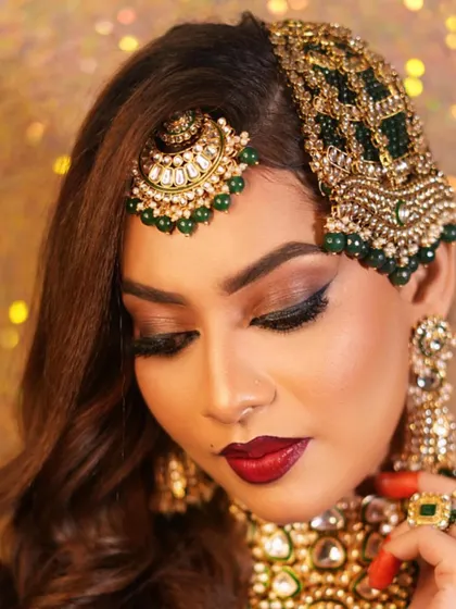A beautiful profile shot that emphasizes the dramatic winged eyeliner and the shimmer on the eyelids. The rich colors of the jewellery and the deep red lip complete this stunning bridal look.