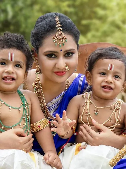 A close-up of a mother with her two adorable little Krishnas, showcasing the intricate details of their costumes and the joy on their faces.