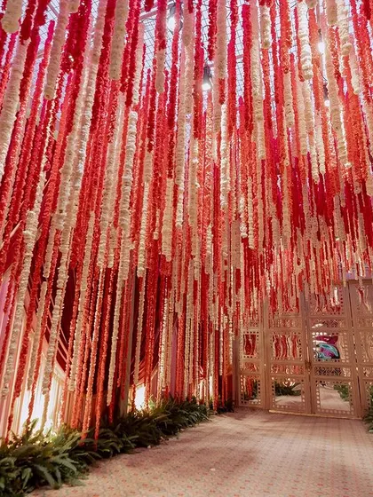 We designed a dramatic entryway for this wedding with a ceiling of hanging red and white floral strings. This immersive tunnel creates a vibrant and celebratory welcome for guests.