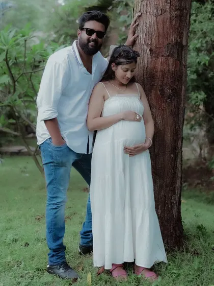 This classic couple maternity pose highlights the connection between the partners and their unborn child in a serene, green environment.