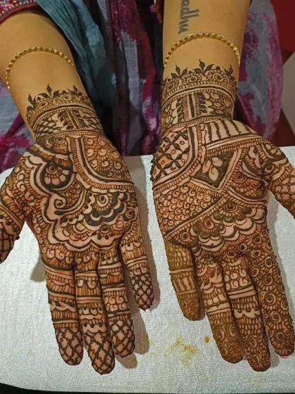 This festive mehendi covers the entire hand and wrist with a beautiful mix of traditional elements. The patterns are dense but clearly defined, showcasing clean and precise application.