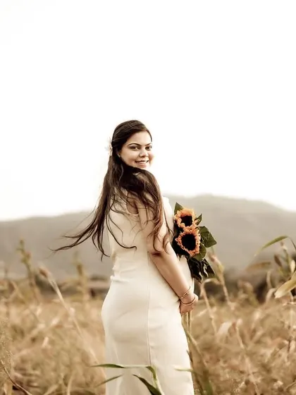 A beautiful portrait of the mom-to-be looking back over her shoulder with a smile, her hair blowing in the wind. The field and mountains provide a stunning natural backdrop.