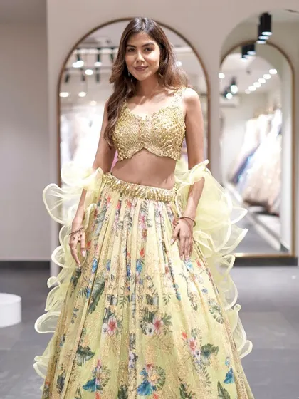 Festive florals and timeless luxury. This light yellow floral lehenga with a heavily embellished gold blouse is elegance in full bloom.