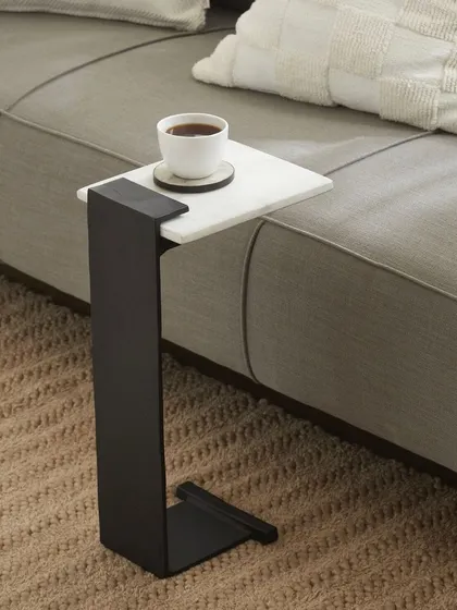 A C-shaped side table designed to slide over a sofa cushion. This shot clearly demonstrates the product's clever functionality and modern design.