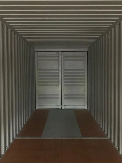 Looking down the length of an empty container toward the sealed cargo doors. This vast, open space is the starting point from which we can build any floor plan you can envision.