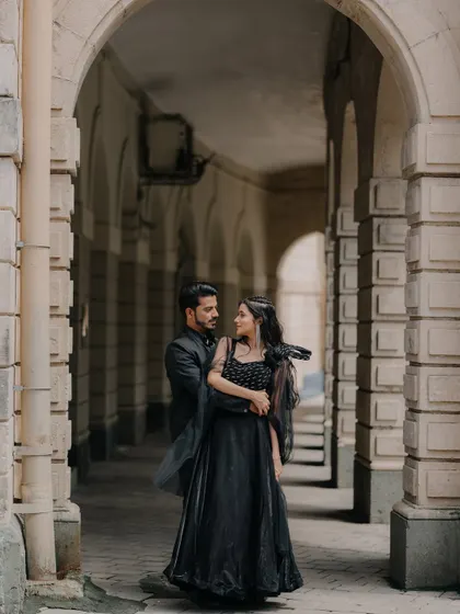 A candid moment of the couple sharing a look within an architectural corridor. The play of light and shadow adds to the romantic, story-like feel of the photograph.