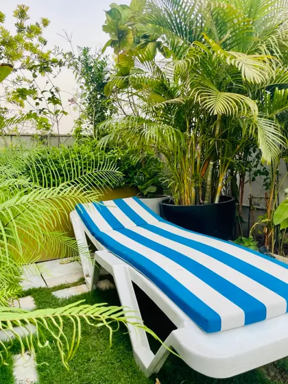 A terrace with a real lawn is a perfect place to chill and sunbathe during winter. A comfortable lounger with blue and white striped cushions is the ideal piece of furniture for relaxation.