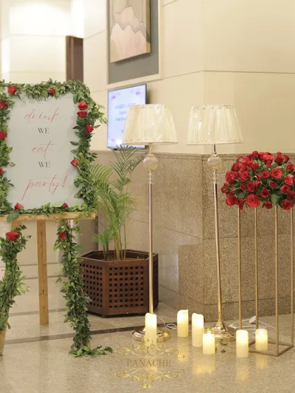 The entrance decor for the after-party, featuring the welcome sign, floor lamps, and arrangements of red roses.