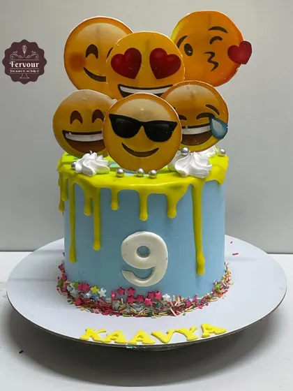 A fun emoji-themed cake for a 9th birthday. The blue cake features a yellow drip and is topped with various smiling and laughing emoji faces.