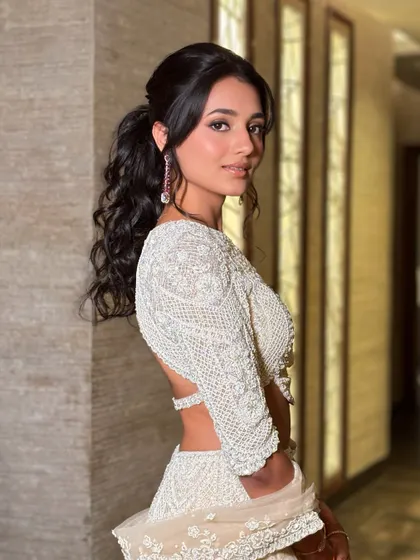 A beautiful portrait of Kopal showing off her reception look. The soft, romantic curls in her ponytail add a touch of elegance to the modern silhouette.