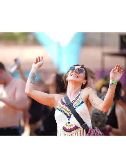 A moment of pure bliss. This woman, with her arms raised and a smile on her face, embodies the free-spirited energy of a festival.