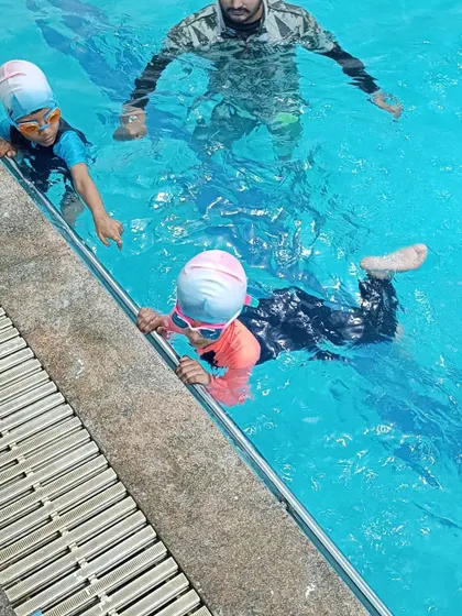 Young learners practicing their kicks along the side of the pool, a fundamental drill in our kids' swimming classes.