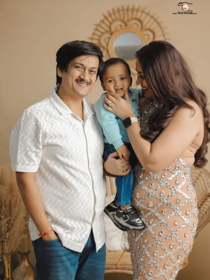 A sweet interaction where the mother gently holds her son's face. The father looks on with a smile, creating a candid family portrait that feels natural and full of affection.